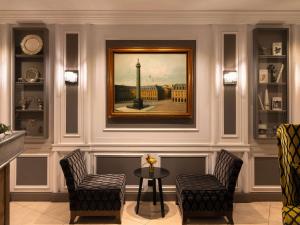巴黎Hotel Stendhal Place Vendôme Paris - MGallery的一间设有两把椅子和一张桌子的房间,还有一幅画