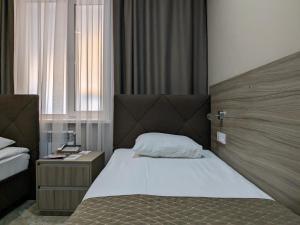 乌拉尔斯克Victoria Hotel的一间卧室配有一张带木制床头板的床