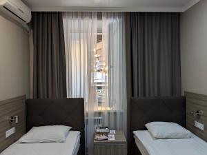 乌拉尔斯克Victoria Hotel的配有窗户的酒店客房内的两张床