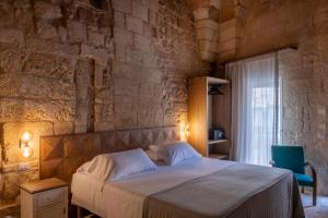 莱切Palazzo Sant'Anna Lecce的一间卧室设有一张床和石墙