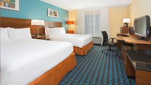 米尔福德Fairfield Inn & Suites by Marriott Boston Milford的酒店客房设有两张床、一张桌子和一台电脑。