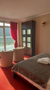 杜博瓦乡Pensiunea Decebal Resort - Cazanele Dunarii的一间卧室配有两把椅子、一张床和窗户