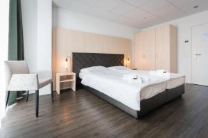 贝尔普Los Lorentes Aparthotel Bern Airport的卧室配有一张白色大床和一把椅子