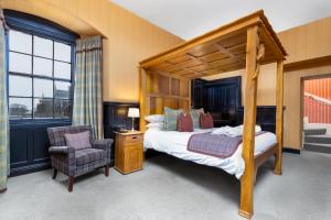 多诺赫多尔诺奇城堡酒店的一间卧室配有一张天蓬床和一把椅子