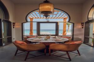 艾阿卡Naama Beach Villas & Spa的一间带桌椅和大窗户的用餐室