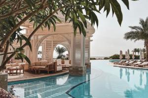 赫尔格达萨尔哈氏男爵宫殿度假村的一个带椅子和棕榈树的度假村游泳池