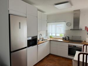 奥德米拉Cabo Sardão Guest House的厨房配有白色橱柜和不锈钢冰箱