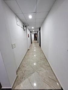 瓜廖尔AMALTAAS HOMESTAY的空的走廊,铺有大理石地板,拥有白色的墙壁