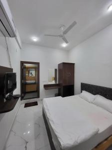 瓜廖尔AMALTAAS HOMESTAY的卧室配有白色的床和电视