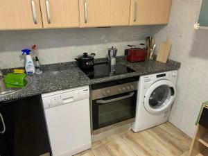 马德里Apartamento completo para 8 personas a 5 minutos del aeropuerto e IFEMA的一间带炉灶的厨房 洗衣机旁的顶级烤箱