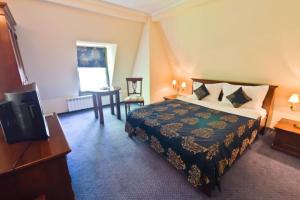 巴克乌Vila Royal的配有一张床和一张书桌的酒店客房