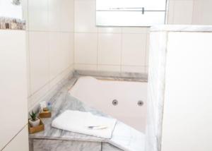 卡内拉Hotel Pousada do Bosque的白色的浴室设有浴缸和窗户。