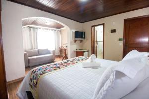 卡内拉Hotel Pousada do Bosque的卧室配有一张白色的大床和一张沙发。