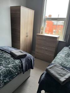 利物浦Lovely 2-Bed House in Liverpool的一间卧室配有一张床、一个梳妆台和一扇窗户。