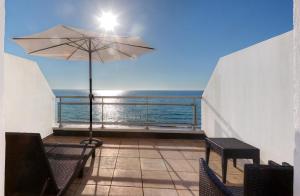 富埃南Garrigae Cap Coz的阳台配有桌子和雨伞。