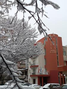 布加勒斯特Hotel Bliss的一座有雪盖的建筑,里面的汽车停在停车场