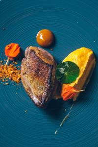 塞尼奥斯亿唐勃朗别墅酒店的一块蓝色的盘子,上面有一块肉和一块橙子
