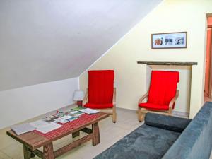Greiveldange吉雷维丹吉公寓的客厅配有2把红色椅子和1张桌子