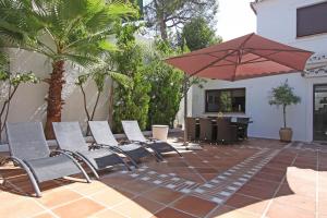 马贝拉1102 Villa with pool ,lounge, BBQ ,direkt in Marbella的庭院里摆放着一组椅子和一把遮阳伞