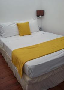 Grand BrasRainbow Inn的一张白色的大床,上面有黄色的毯子