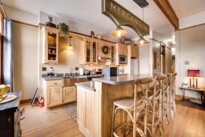 拉勒米Historic DT Laramie Apartment Deck and 1 Mi to UW!的一间带木制橱柜的厨房和一间带凳子的酒吧