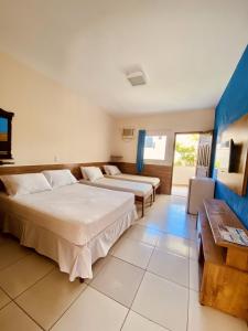 塞古罗港Hotel Porto das Ancoras的酒店客房设有两张床和一张桌子。