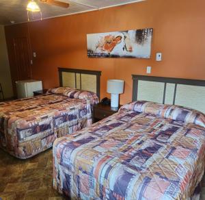 里穆斯基Motel Au Soleil couchant的橙色墙壁的酒店客房内的两张床