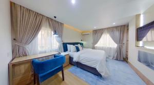 阿布贾C. Apartments Annex的一间卧室配有一张床、一张书桌和两个窗户。