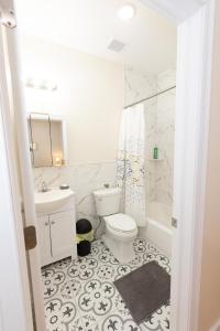 泽西市Elegant Modern 3-Bed Apt near NYC的白色的浴室设有卫生间和水槽。