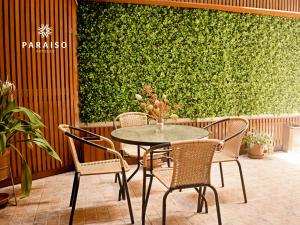 齐克拉约Hoteles Paraiso CHICLAYO的绿色墙壁前的桌椅