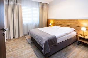 绿山城NOVY Hotel的一间卧室配有一张大床和木制床头板