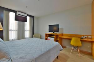 巴西利亚Comfort Hotel Taguatinga - Flat Preferido c/ Wifi的一间卧室配有一张床、一张书桌和一台电视