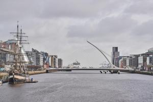 都柏林Sonder at Britain Quay的一座建有建筑物的城市里河流上的桥梁