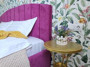 阿拉木图ЖК ATREA 2 room Apartment的一张带紫色床头板的床和一张带鲜花的桌子
