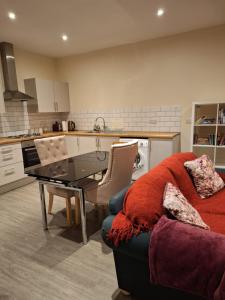 朗伊顿Fabulous Home from Home - Central Long Eaton - Lovely Short-Stay Apartment - HIGH SPEED FIBRE OPTIC BROADBAND INTERNET - HIGH SPEED STREAMING POSSIBLE Suitable for working from home and students Very Spacious FREE PARKING nearby的客厅配有沙发和餐桌,厨房配有桌子