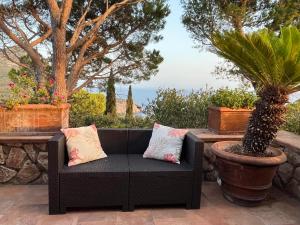 蒙泰亚尔真塔廖Panorama mozzafiato Argentario - Cala Piccola的一张黑色沙发,坐在种有植物的庭院里