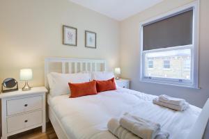 伦敦Stunning 4 Bedroom House的卧室配有白色床、橙色枕头和窗户