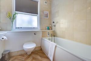 伦敦Stunning 4 Bedroom House的一间带卫生间和浴缸的浴室以及窗户。