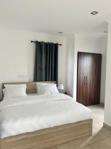 阿克拉Stay Play Away Residences - Luxury 4 bed, Airport Residential, Accra的一间卧室配有一张大床和一个木制橱柜