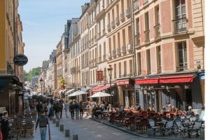 凡尔赛B&B rue Royale Versailles的一条繁忙的城市街道,人们在散步,桌子和椅子