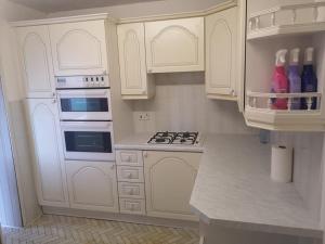 卢顿MossBank House Luton Airport的厨房配有白色橱柜和炉灶烤箱。