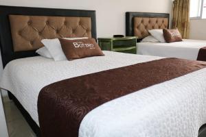 波哥大Hotel Casa Botero 302的酒店客房,设有两张白色和棕色的床