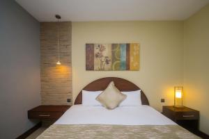 内罗毕Taarifa Suites by Dunhill Serviced Apartments的一间卧室配有一张带白色床罩和两盏灯的床。