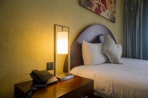 内罗毕Taarifa Suites by Dunhill Serviced Apartments的一间酒店客房,配有一张床铺和一张桌子上的电话