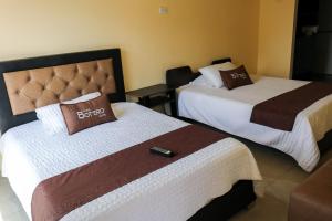 波哥大Hotel Casa Botero 305的配有遥控器的酒店客房内的两张床