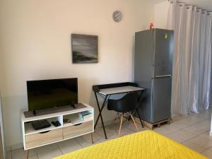 卡宴Le nid du Kikiwi , refuge relaxant avec jardin的配有电视、桌子和椅子的房间