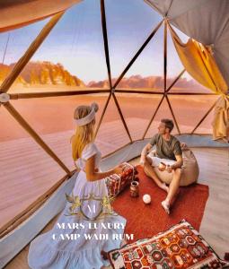 瓦迪拉姆MARS lUXURY CAMP WADI RUM的坐在帐篷里的男人和女人