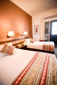 库斯科Hotel Raymi的酒店客房设有两张床和窗户。