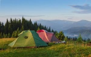 武吉丁宜Tapian Asri Camp的两顶帐篷位于山丘上,山丘背景