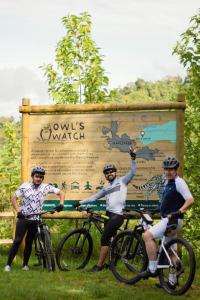 马尼萨莱斯Owl's Watch Nature Retreat的一群三人骑着自行车,站在标志前